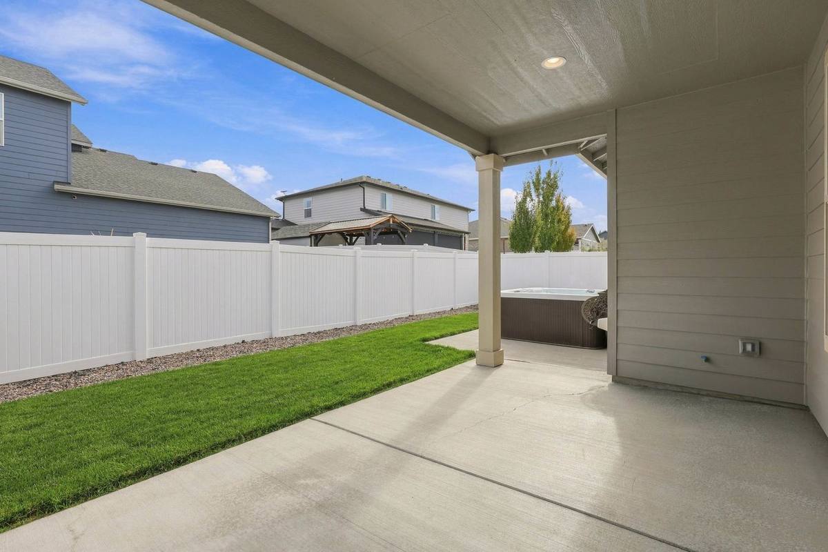 Extended covered patio overlooking the fenced lawn